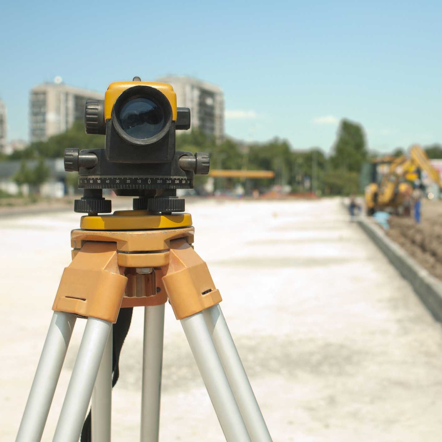 Surveying equipment to infrastructure construction project. Excavator on the background